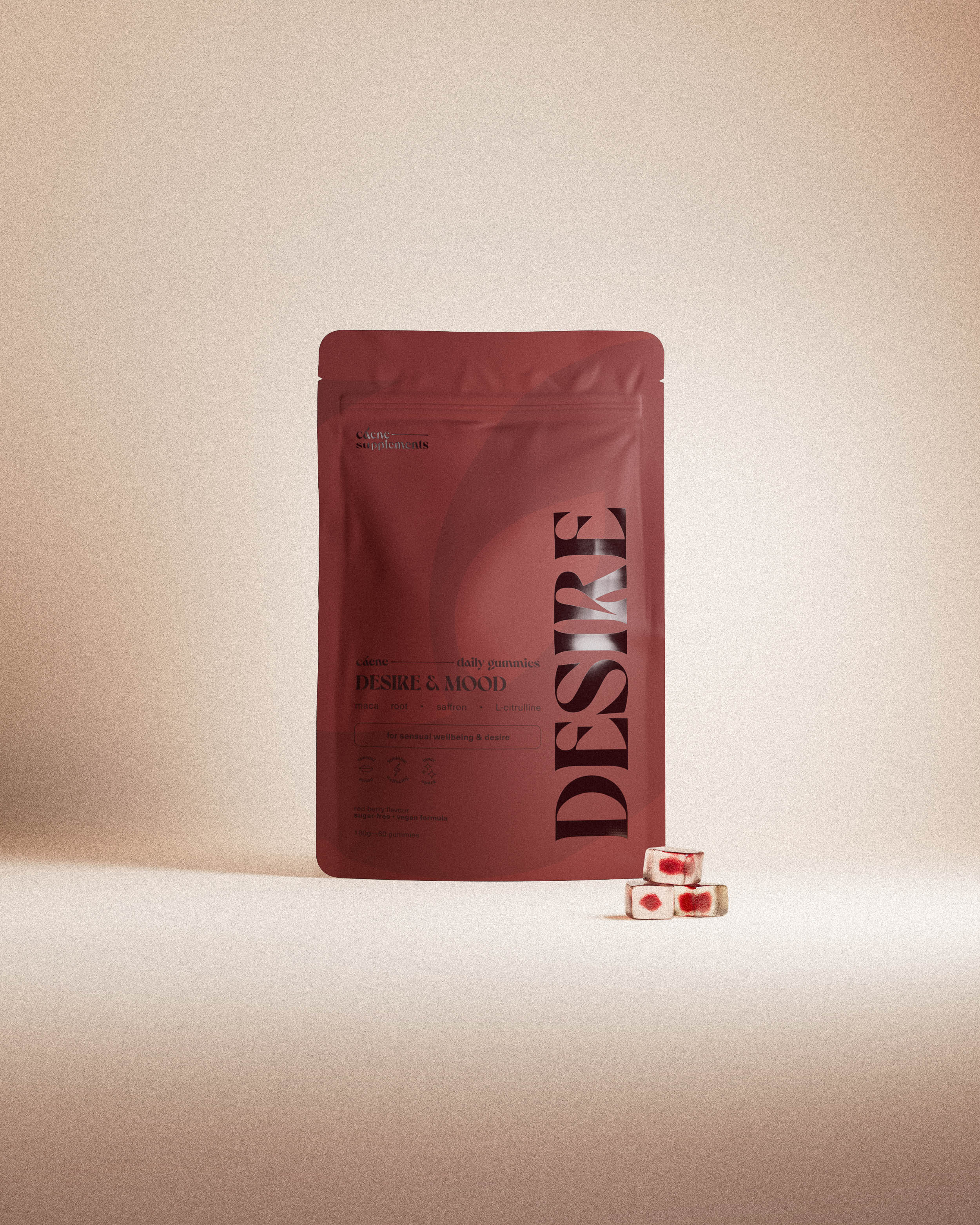 desire gummies pouch with three red gummies in a warm studio setting