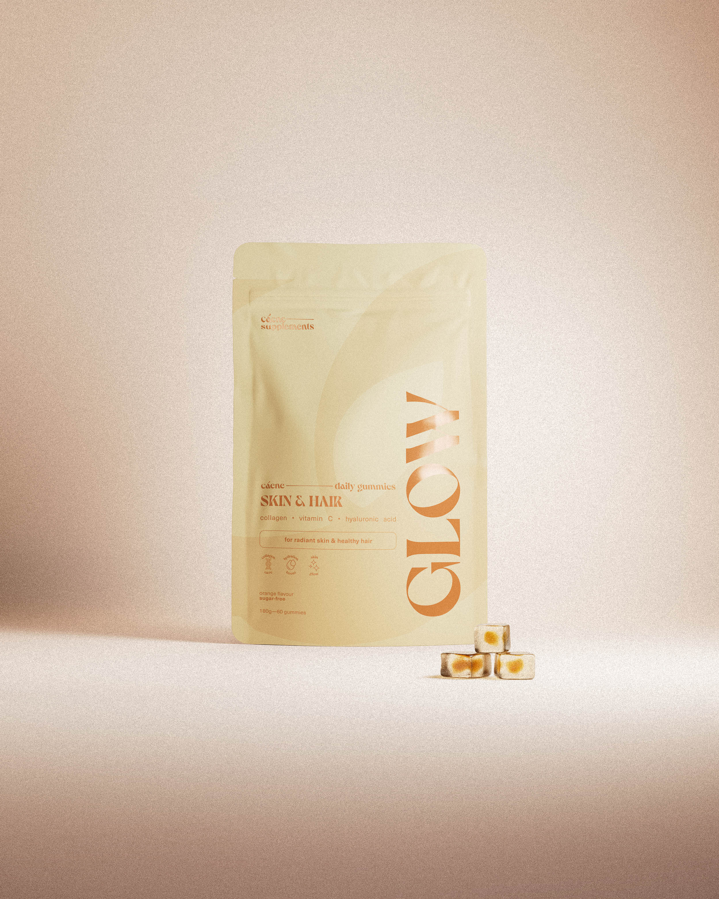 glow gummies pouch with three orange gummies in a warm studio setting